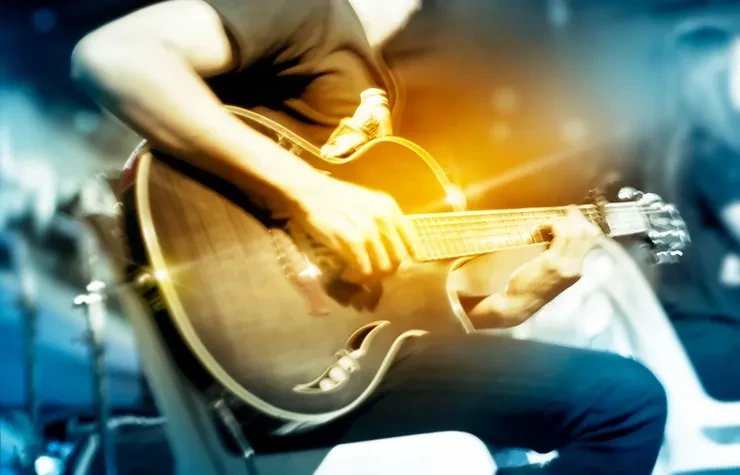 Musician playing acoustic guitar with golden stage lighting