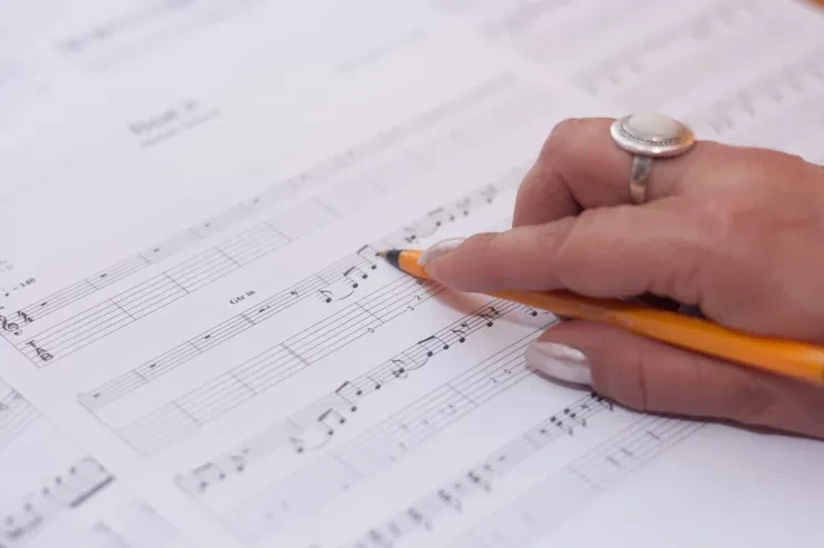 Hand with pencil annotating sheet music
