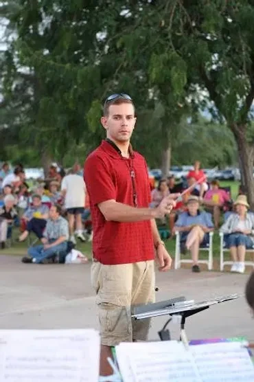 Conductor leading the band at an outdoor park concert